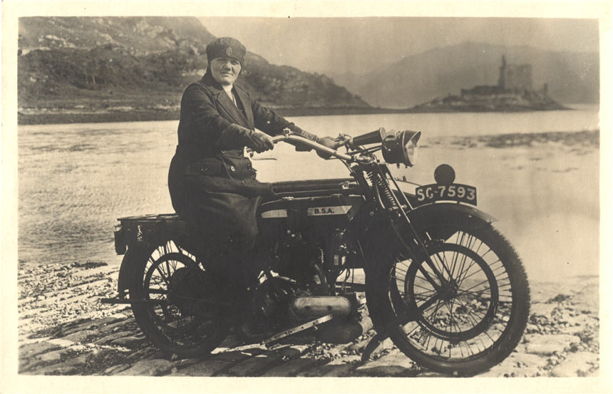 Eine weiße Krankenschwester auf einem Motorrad blickt den Betrachter an, im Hintergrund das Schloss.